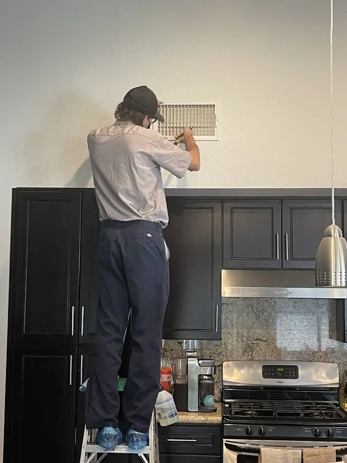 Technician inspecting an air vent during HVAC service in Richmond